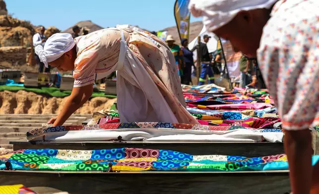 南非政府通訊及資訊服務處提供的照片顯示，2026年3月23日周一，在南非斯泰因科普夫（Steinkopf），婦女在重新安葬數十具非洲人遺骸的儀式上，用傳統布料覆蓋棺木。這些遺骸早年被挖掘並運往歐洲作科學研究。(賈魯斯·穆特爾/南非政府通訊及資訊服務處 via 美聯社) AP圖片
