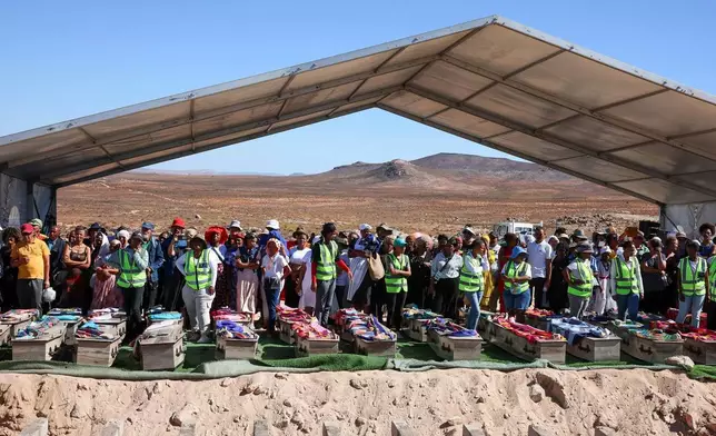 南非政府通訊及資訊服務處提供的照片顯示，2026年3月23日周一，在南非斯泰因科普夫（Steinkopf），家人和社區成員在重新安葬數十具非洲人遺骸的儀式上站在棺木後方。這些遺骸早年被挖掘並運往歐洲作科學研究。(賈魯斯·穆特爾/南非政府通訊及資訊服務處 via 美聯社) AP圖片