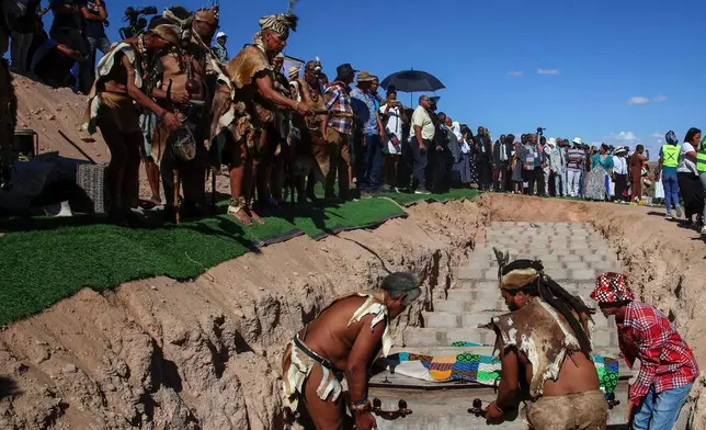 南非政府通訊及資訊服務處提供的照片顯示，2026年3月23日周一，在南非斯泰因科普夫（Steinkopf），男子在重新安葬數十具非洲人遺骸的儀式上將棺木放入墓穴。這些遺骸早年被挖掘並運往歐洲作科學研究。(賈魯斯·穆特爾/南非政府通訊及資訊服務處 via 美聯社) AP圖片