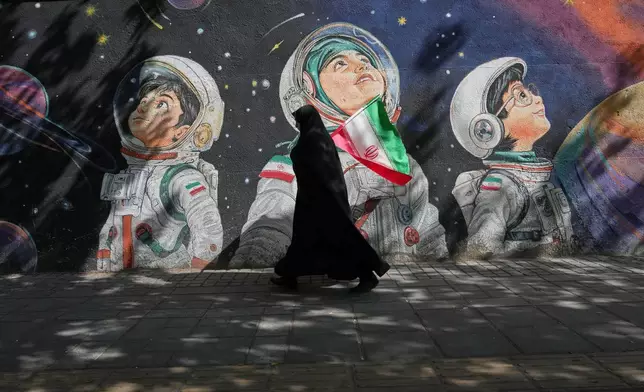 資料圖片：2026年4月8日周三，在伊朗（Iran）德黑蘭（Tehran），一名女子走過一幅壁畫。(美聯社圖片/Francisco Seco, File) AP圖片
