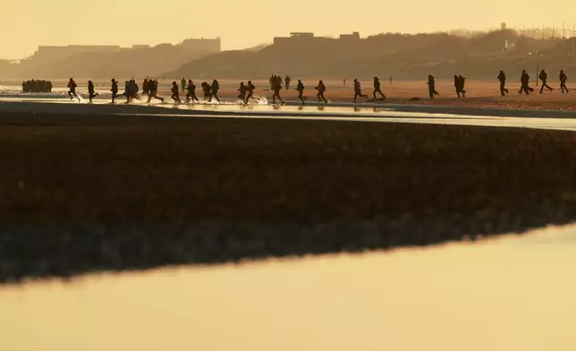 資料圖片：2026年4月8日周三，在法國（France）北部馬洛萊班（Malo-les-Bains），移民奔跑著登上小船，試圖前往英國（Britain）。(美聯社圖片/Jean-Francois Badias, File) AP圖片