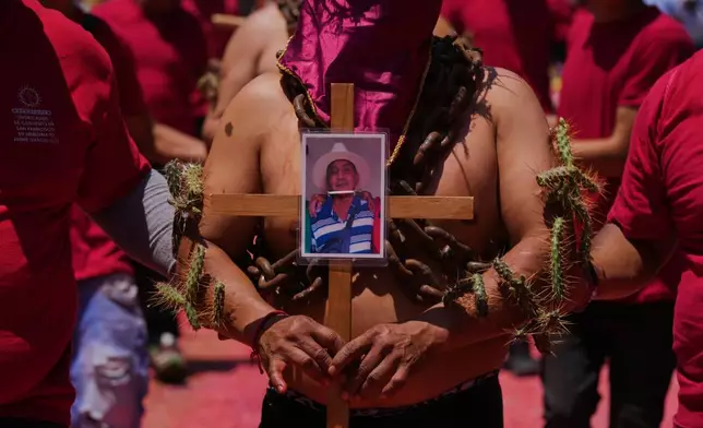 一名身披鎖鏈、黏着仙人掌刺的懺悔者，於2026年4月3日周五墨西哥阿特利斯科的聖周耶穌受難日巡遊中，手持十字架上的照片。(美聯社圖片/Fernando Llano) AP圖片