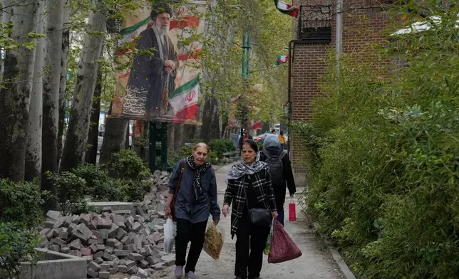 2026年4月12日周日，婦女走過伊朗德黑蘭北部一幅已故伊朗最高領袖哈梅內伊的橫額，他於2月28日在美國和以色列的襲擊中喪生。(美聯社圖片/Vahid Salemi) AP圖片