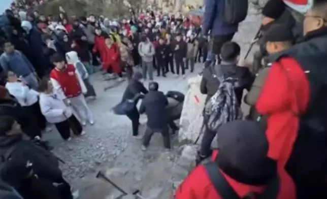 泰山遊客為爭奪觀賞日出位爆肢體衝突，一男子遭飛踢滑落岩石邊。影片截圖