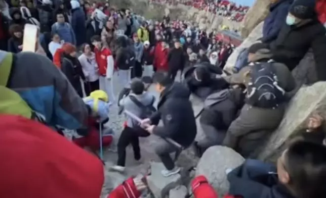 泰山遊客為爭奪觀賞日出位爆肢體衝突，一男子遭飛踢滑落岩石邊。影片截圖