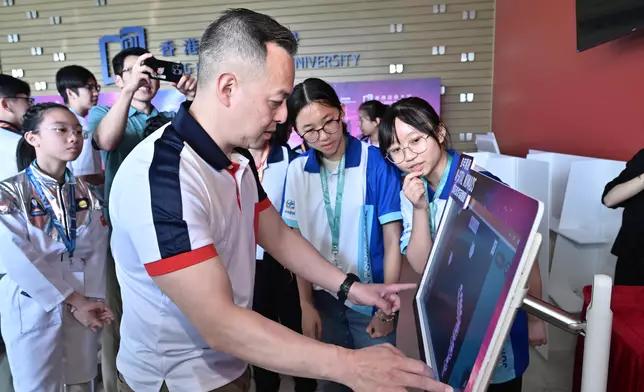 中學組冠軍得主向警務處處長周一鳴（左）介紹得獎作品。