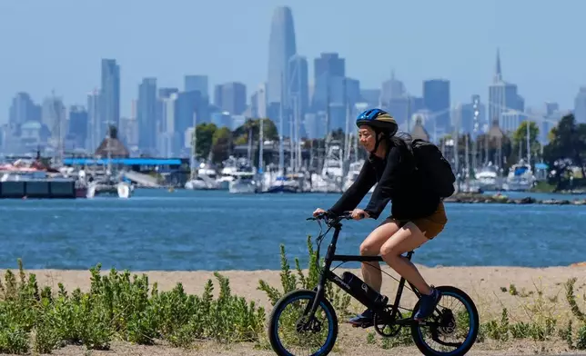 (美聯社圖片/戈多弗雷多A.華斯基斯) 2025年8月19日，加州阿拉米達，一名女子在小徑上騎單車，背景可見三藩市（San Francisco）天際線。 AP圖片