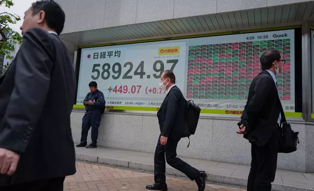 2026年4月20日周一，人們在日本東京（Tokyo）一間證券公司前，走過顯示日本日經指數的電子股價板。(美聯社圖片/Eugene Hoshiko) AP圖片