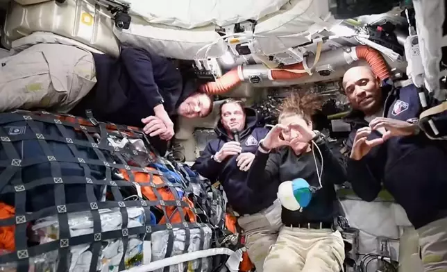 4月2日，美國太空總署提供的影片截圖顯示，「阿提米絲2號」任務指揮官懷斯曼（左二）在前往月球途中，透過視像會議向美國太空總署任務控制中心發言。加拿大太空人兼任務專員漢森（左一）在旁觀看，任務專員科赫(右二)及機師格洛弗（右一）則用手比出心形。 AP圖片