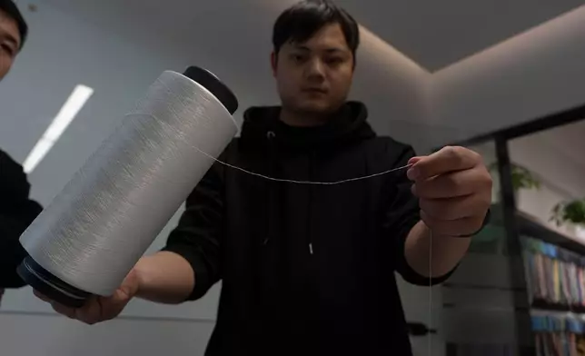 一名工人在中國東部江蘇省張家港一間紡織品分揀設施內，展示由回收合成紡織品製成的加工聚酯纖維紗線。該設施採用弓葉科技（DataBeyond）的Fastsort-Textile（快速分類紡織）AI分揀機。攝於2026年3月20日。(美聯社圖片/Ng Han Guan) AP圖片