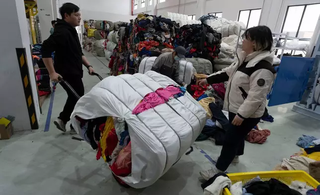 工人在中國東部江蘇省張家港一間紡織品分揀設施內搬運成堆的舊衣物。該設施採用弓葉科技（DataBeyond）的Fastsort-Textile（快速分類紡織）AI分揀機。攝於2026年3月20日。(美聯社圖片/Ng Han Guan) AP圖片