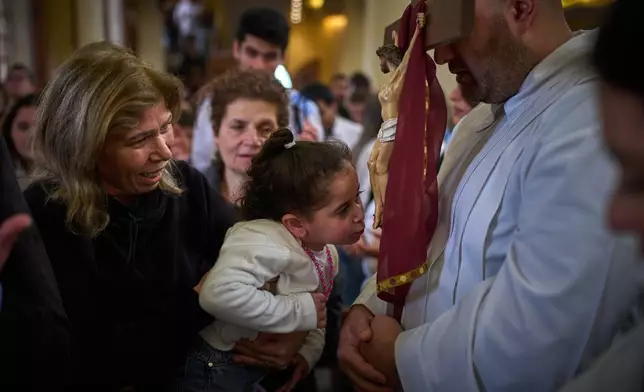 2026年4月3日周五，黎巴嫩貝魯特郊區傑代德的聖安東尼教堂舉行耶穌受難日彌撒，一名女孩親吻神父手中的十字架。是次彌撒旨在聲援因戰爭而流離失所的黎巴嫩南部基督徒村民。(美聯社圖片/Emilio Morenatti) AP圖片
