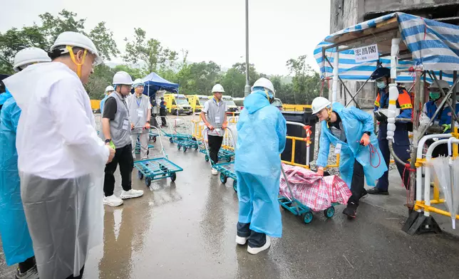 政務司副長卓永興（左）觀看民安隊隊員和動員公務員聯同地區服務及關愛隊伍義工，協助居民搬運物品。政府新聞處圖片