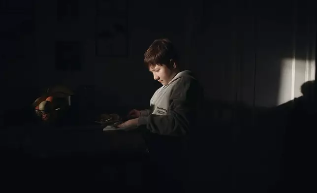 周二（2026年3月17日），11歲的古爾哈約·尤爾多舍娃（Gulhayo Yuldosheva）的兒子赫里貝托（Heriberto）在紐約市布朗克斯區一棟公寓大廈一邊吃早餐一邊使用手機，該處租客反映維修問題及蟲害。 (美聯社圖片/安德烈斯·庫達奇) AP圖片