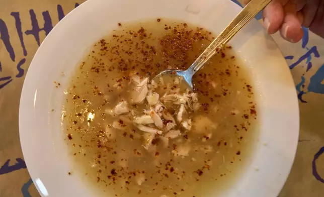 2026年4月3日周五，一名女子在雅典市中心Epirus餐廳準備享用傳統牛肚湯，該湯在希臘被稱為「帕特薩湯」（patsas），在土耳其則稱為「伊斯肯貝湯」（iskembe）。 (美聯社圖片/Petros Giannakouris) AP圖片