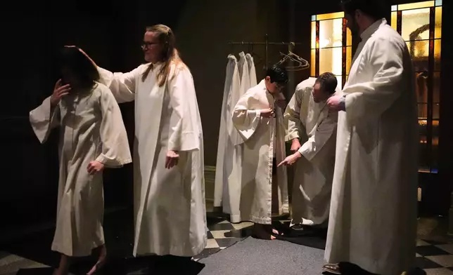 周六（2026年4月4日），新受洗者在西雅圖（Seattle）聖雅各伯座堂（St. James Cathedral）舉行的復活節守夜儀式上受洗後，穿上他們的新白袍。（美聯社圖片/Lindsey Wasson） AP圖片