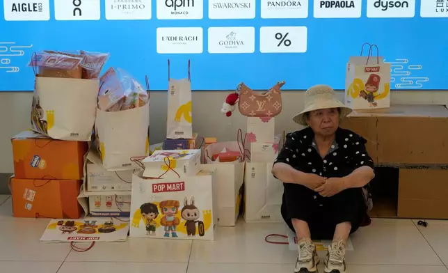 2025年6月13日，周五，北京，一名女子在商場內泡泡瑪特（PopMart）的Labubu商品袋旁休息。(美聯社圖片/Ng Han Guan) AP圖片