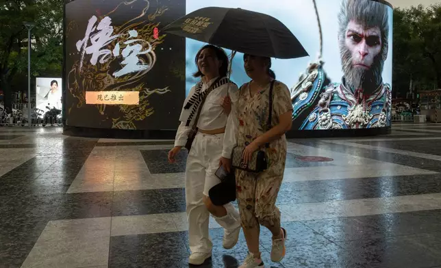2024年8月23日，周五，北京，兩名女子撐傘經過宣傳中國大製作電子遊戲《黑神話：悟空》（Black Myth: Wukong）的廣告。(美聯社圖片/Ng Han Guan) AP圖片