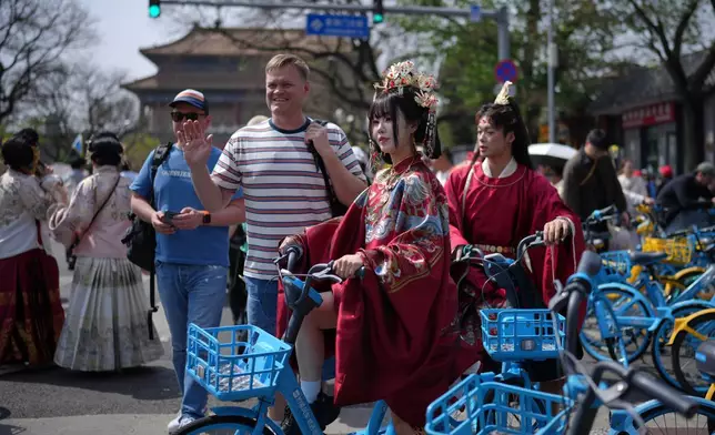 2026年4月12日，周日，北京，一名外國遊客在故宮附近與一對身穿帝王服飾的中國夫婦合影。(美聯社圖片/Andy Wong) AP圖片