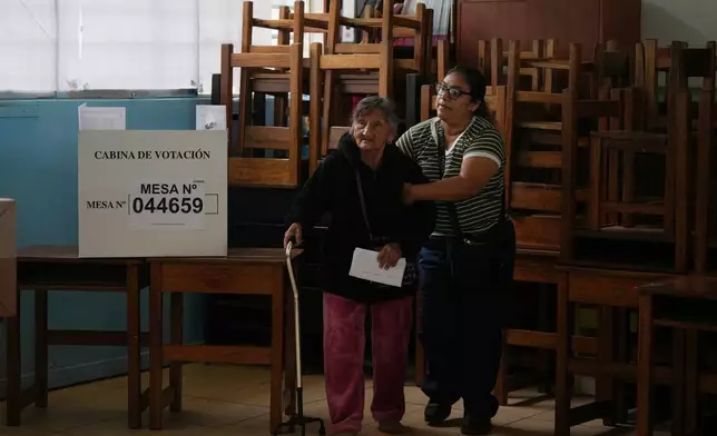 一名親屬協助一名婦女投票。周一（2026年4月13日），受延誤及物流問題影響的投票站恢復運作，進行秘魯（Peru）利馬（Lima）大選投票。(美聯社圖片/Guadalupe Pardo) AP圖片