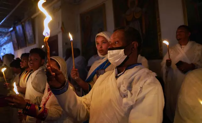 2026年4月11日周六，在華盛頓的聖瑪麗亞教堂（Re’ese Adbarat Debre Selam Kidist Mariam Church），一座埃塞俄比亞東正教特瓦赫多教堂，信眾在復活節禮拜期間手持點燃的蠟燭（tuaf），象徵復活的時刻，他們相信基督之光驅散了黑暗。(美聯社圖片/Jessie Wardarski) AP圖片