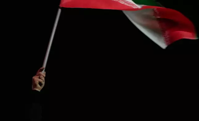 資料圖片：2026年3月25日，在伊朗德黑蘭（Tehran）西部一個廣場舉行的親政府集會上，一名女子揮舞伊朗國旗，手持已故伊朗最高領袖阿亞圖拉阿里哈梅內伊（Ayatollah Ali Khamenei）的肖像，並高呼口號。(美聯社圖片/Vahid Salemi) AP圖片