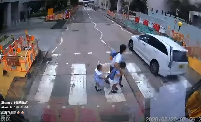 一名女傭帶着兩名身穿校服的幼童橫過斑馬線期間，一輛白色私家車逆線直衝而過，幸女傭及時拉住幼童，避過一劫。車cam L（香港群組）FB群組視頻截圖