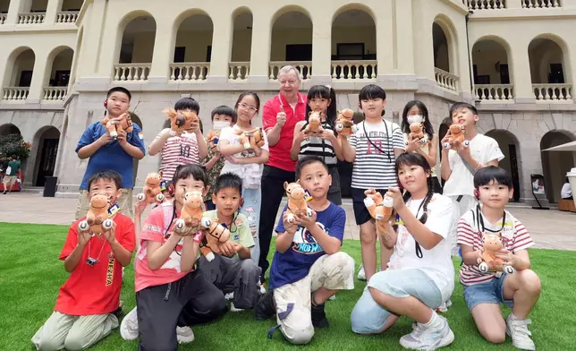 香港賽馬會行政總裁應家柏（後排右五）與其他馬會義工帶領參與活動的家庭，參觀及介紹大館的歷史及特色。