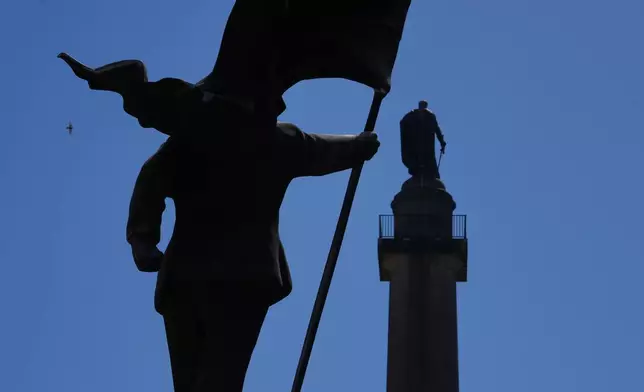 倫敦滑鐵盧廣場（Waterloo Place）周四（2026年4月30日）出現一座雕塑，描繪一名男子手持旗幟遮蓋臉部（左），並簽有「Banksy」字樣。（美聯社圖片/Kin Cheung） AP圖片