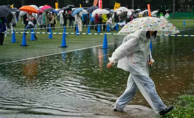 2026年5月1日周五，一名工會成員在東京的雨中小心翼翼地穿過積水，參與五一勞動節集會。(美聯社圖片/Eugene Hoshiko) AP圖片