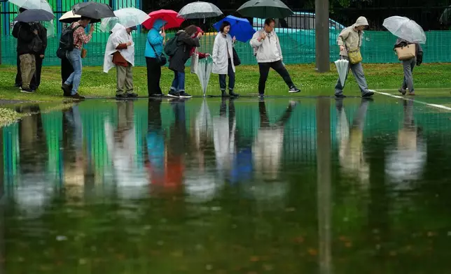 2026年5月1日周五，工會成員在東京冒雨小心翼翼地穿過積水，參與五一勞動節集會。(美聯社圖片/Eugene Hoshiko) AP圖片