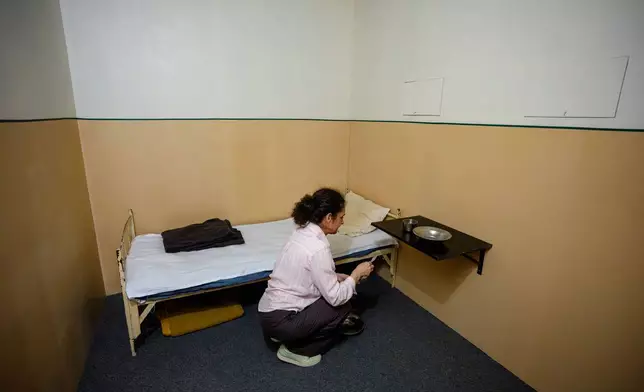羅馬尼亞國家安全部檔案研究委員會（CNSAS）歷史學家奧安娜·德梅特里亞德，在2026年6月15日周一，羅馬尼亞布加勒斯特羅馬尼亞國家歷史博物館舉行的「A.REST 1989 — 秘密警察錄像檔案」展覽開幕前一天，為秘密警察囚室複製品作最後修飾。(美聯社圖片/安德烈亞·亞歷山德魯) AP圖片