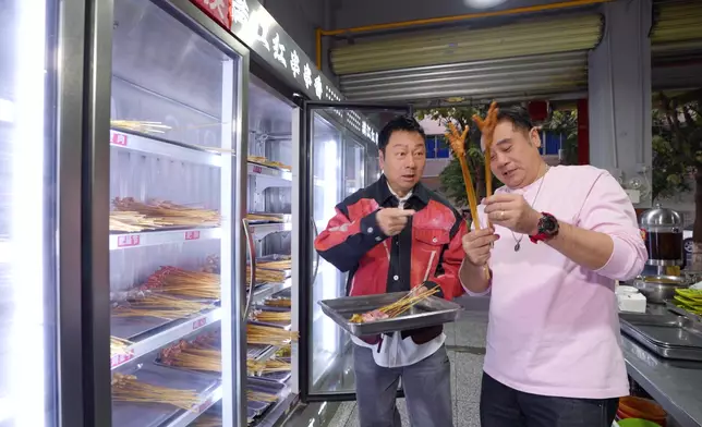 兩人品嘗價廉物美的「串串香」。