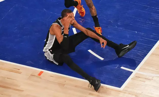 紐約時間2026年6月10日周三，NBA總決賽第四場比賽上半場，聖安東尼奧馬刺隊前鋒維克托·文班亞馬在紐約對陣紐約人隊時被撞倒後坐在地上。(美聯社圖片/法蘭克·富蘭克林二世) AP圖片