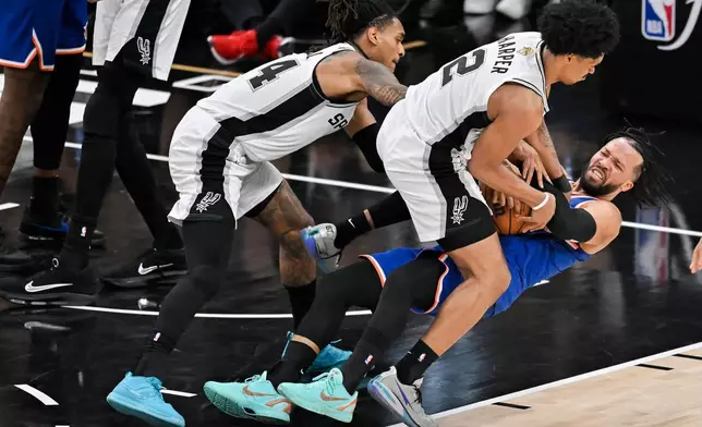 紐約人隊後衛賈倫·布倫森在2026年6月13日周六於聖安東尼奧舉行的NBA總決賽第五場下半場比賽中，受到聖安東尼奧馬刺隊後衛迪倫·哈珀（2號）及後衛德文·瓦塞爾的壓迫後倒地。（美聯社圖片/Darren Abate） AP圖片
