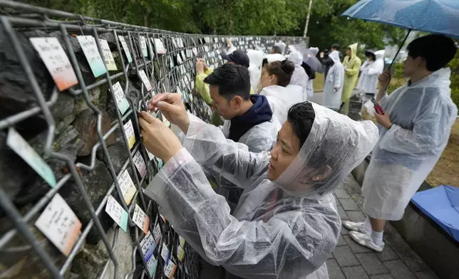 南韓被領養者與南韓義工，2026年5月20日在南韓坡州Omma Poom公園的名牌牆上掛上名牌。(美聯社圖片/Ahn Young-joon) AP圖片