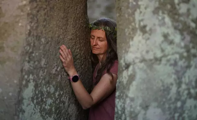 一名狂歡者在英格蘭索爾茲伯里附近古老石圈巨石陣觸摸石塊，慶祝夏至，即一年最長的一天，2026年6月20日周六。(美聯社圖片/Alberto Pezzali) AP圖片