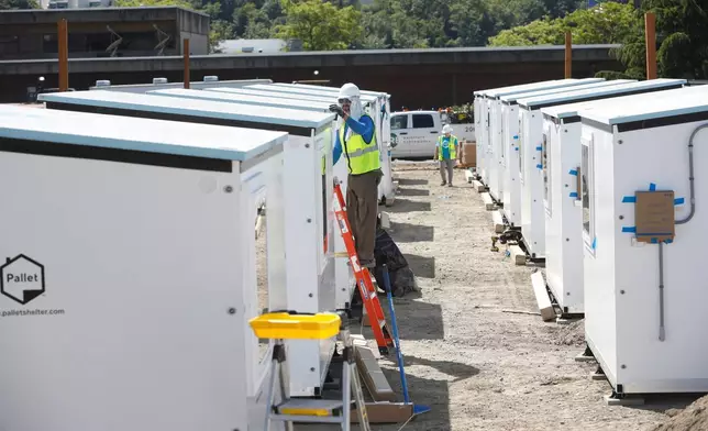 一名工人在西雅圖檢查一個正在安裝的Pallet Shelter單位頂部，攝於2026年5月28日周四。這些由複合板製成的單人床單位，是西雅圖市長凱蒂·威爾遜擴大該市露宿者收容所計劃的一部分。(美聯社圖片/Manuel Valdes) AP圖片