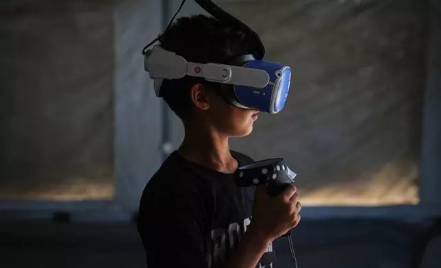 11歲的穆罕默德·馬塔爾，周三（2026年6月17日）在加沙地帶中部扎瓦伊達一個由醫療科技團隊營運的帳篷內，利用虛擬實境（VR）頭戴式裝置參與心理支援環節。(美聯社圖片/Abdel Kareem Hana) AP圖片
