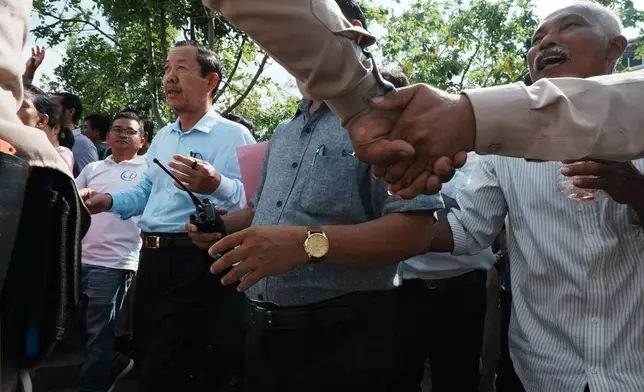 保安人員手牽手築成人牆，保護柬埔寨著名反對派政治人物榮春（左後方），他周一（2026年6月15日）在柬埔寨金邊最高法院聽證會後，與支持者一同穿過公園。（美聯社圖片/Heng Sinith） AP圖片
