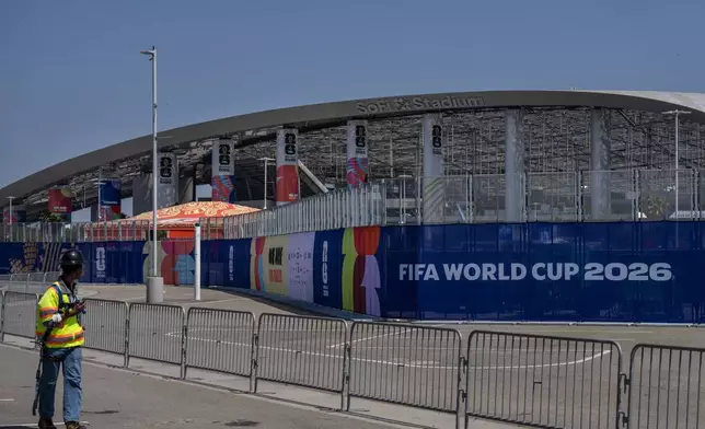 一名工人在加州英格爾伍德SoFi體育場外，走過設有2026年世界盃標誌的臨時圍欄。攝於2026年6月5日周五。(美聯社圖片/Jae C. Hong) AP圖片