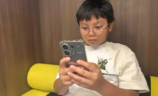 十一歲的Hew Chee Weng周一在馬來西亞吉隆坡使用智能手機。(美聯社圖片/Syawalludin Zain) AP圖片