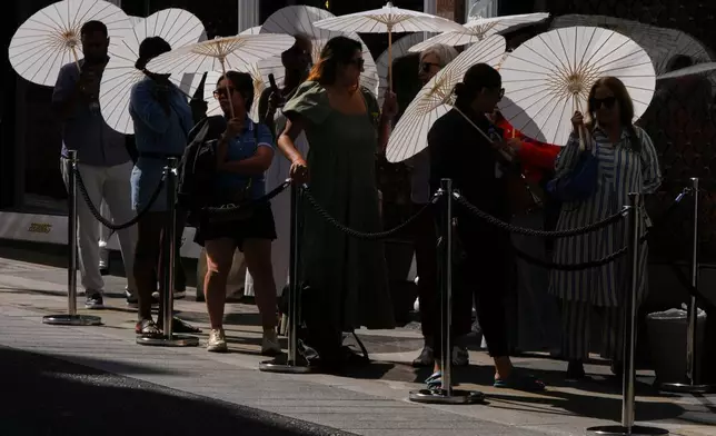 2026年6月26日周五，倫敦，民眾在商店外排隊時使用太陽傘遮擋陽光。(美聯社圖片/Kirsty Wigglesworth) AP圖片