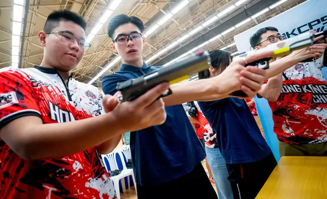 體育節大使曾湛元與林依諾在運動工作人員指導下練習射擊運動項目