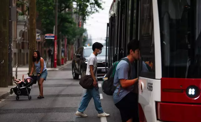 2026年7月15日周三，多倫多市被山火濃煙籠罩，一名戴口罩人士登上電車。(Laura Proctor/加拿大通訊社圖片/美聯社) AP圖片