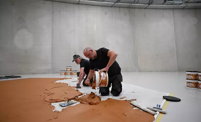 工作人員在地板上塗抹花生醬，重現「花生醬地板」藝術品，向荷蘭藝術家維姆·T·施佩爾斯致敬，攝於荷蘭鹿特丹博伊曼斯·范伯寧恩博物館，2026年7月3日周五。(美聯社圖片/穆內布·泰姆) AP圖片