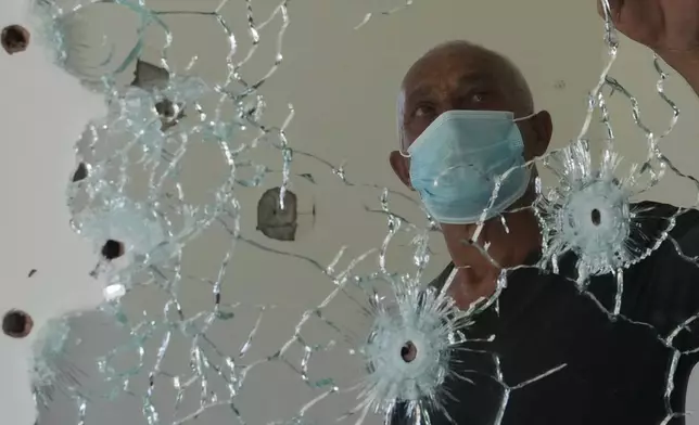 黎巴嫩扎烏塔爾加爾比耶一名居民，在家中一面佈滿彈孔的鏡子後方站立。此前以色列軍方曾於該區採取行動。攝於2026年7月28日周二，黎巴嫩。(美聯社圖片/Hassan Ammar) AP圖片