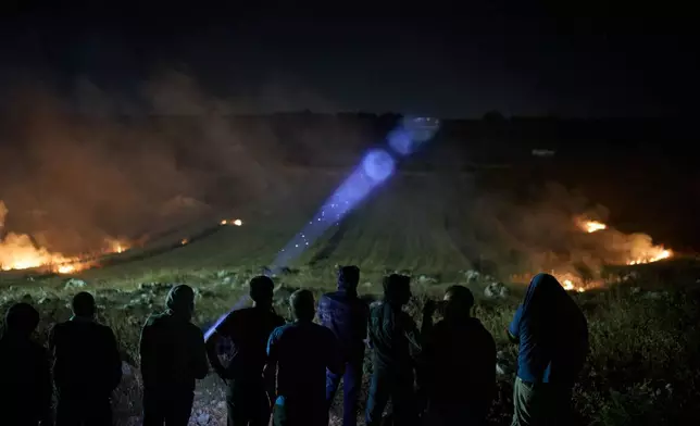 一名巴勒斯坦人使用電筒，此前參與夜間巡邏的志願者發現附近山上有以色列定居者，並點燃灌木叢以阻止他們接近約旦河西岸辛吉爾村莊。2026年7月16日周四。(美聯社圖片/Leo Correa) AP圖片