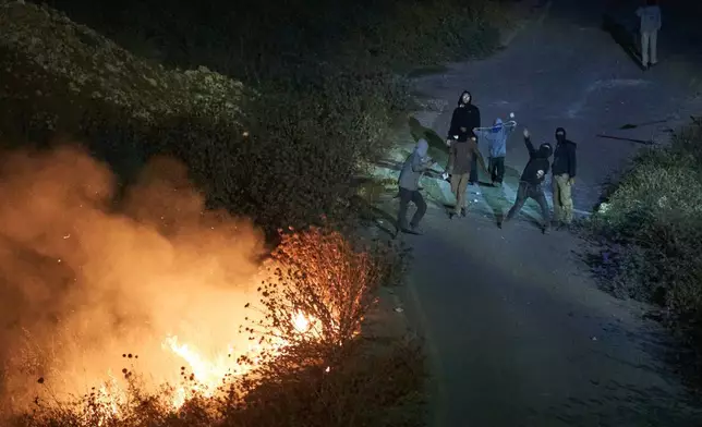 以色列定居者投擲石塊，路邊灌木叢燃燒，此前巴勒斯坦人點燃灌木叢以阻止定居者接近約旦河西岸辛吉爾村莊。2026年7月17日周五。(美聯社圖片/Leo Correa) AP圖片