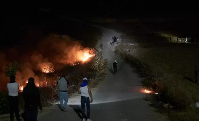 以色列定居者（上方）與巴勒斯坦人爆發衝突，路邊灌木叢燃燒，此前巴勒斯坦人點燃灌木叢以阻止定居者接近約旦河西岸辛吉爾村莊。2026年7月17日周五。(美聯社圖片/Leo Correa) AP圖片